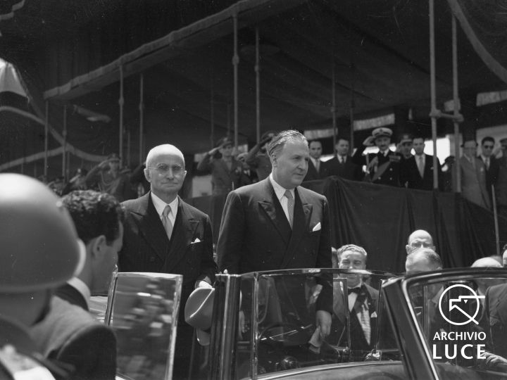 Il presidente Einaudi e il ministro Pacciardi ripresi in piedi, a bordo di un'automobile cabriolet, nei pressi della tribuna autorità in via dei Fori Imperiali, 1951