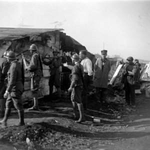 Soldati picconano una baracca; in strada una colonna di sfollati con materassi, coperte, pacchi, 1927