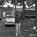 Adriano Celentano, di profilo e con una mano sul fianco, nei viali di Cinecittà, 1959